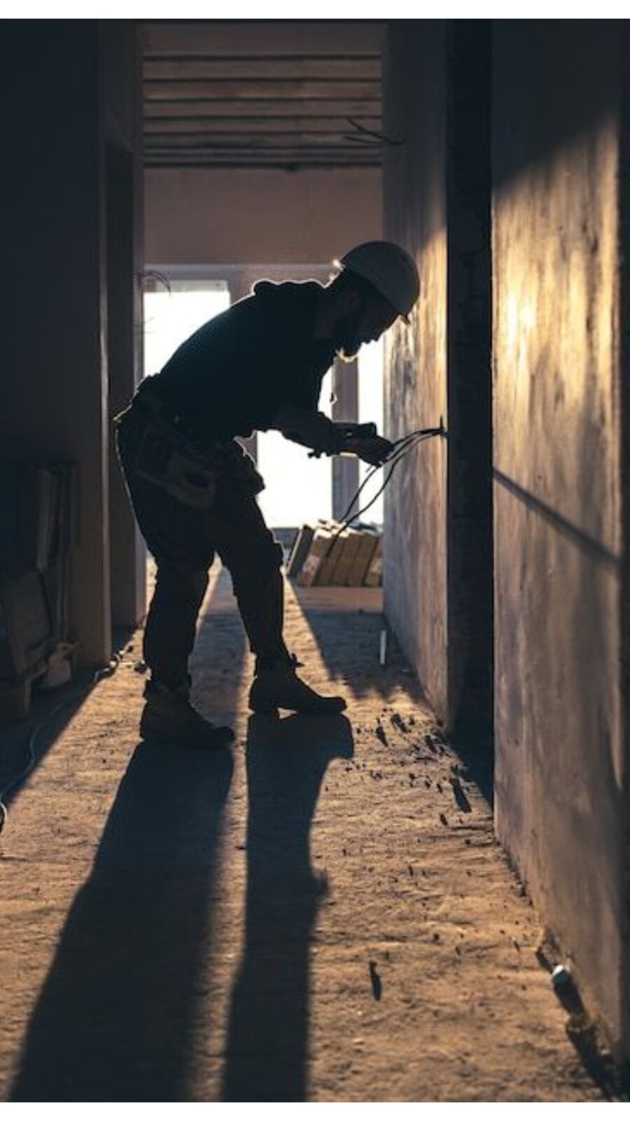 Tradesperson drilling into an interior wall during renovation work.